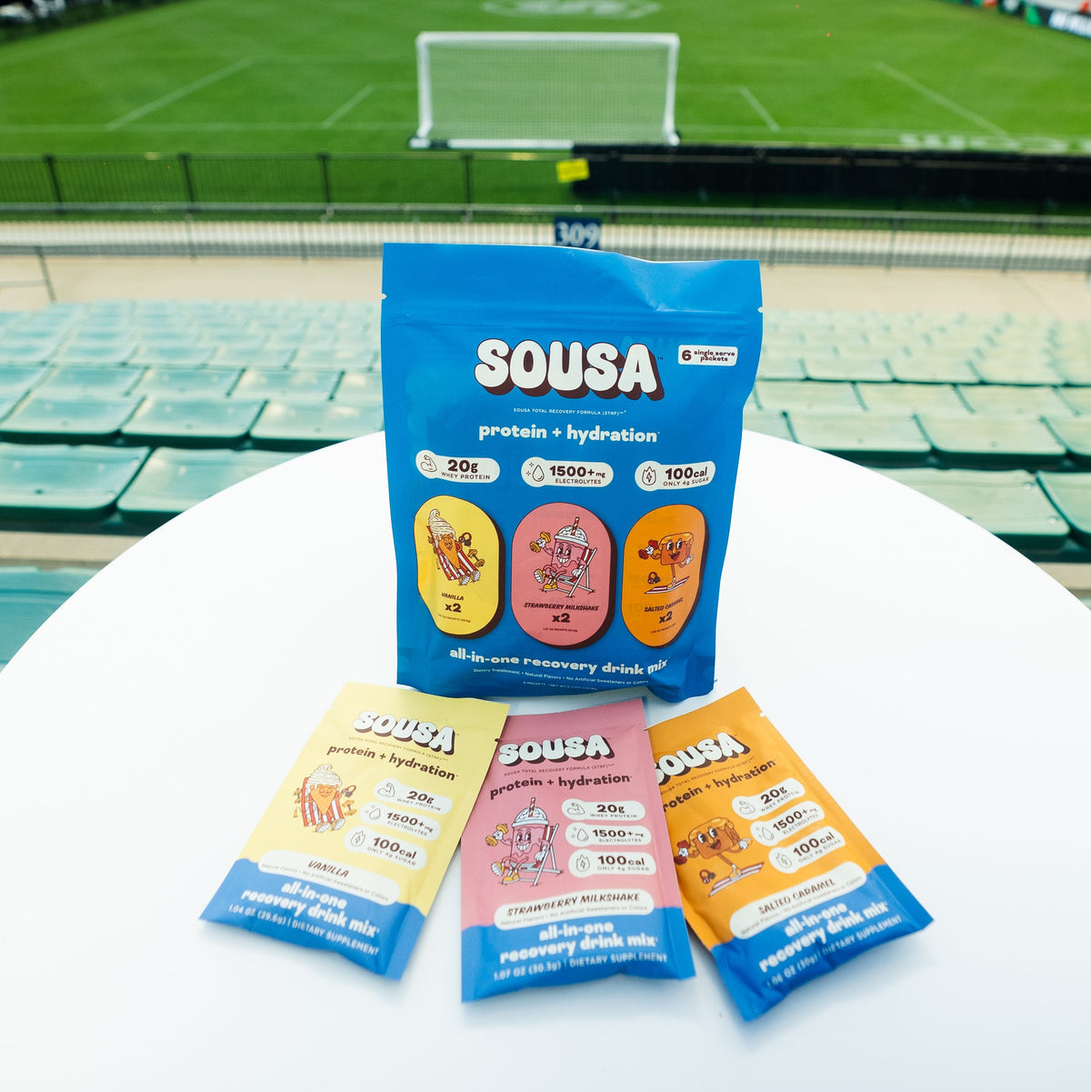 Sousa product packaging on a table with a soccer field in the background
